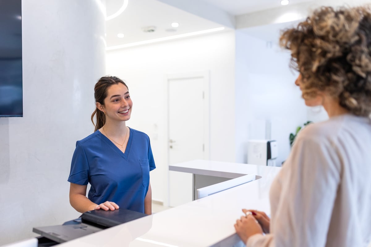 A friendly receptionist welcoming a patient at the Valencia Family Medicine front desk
