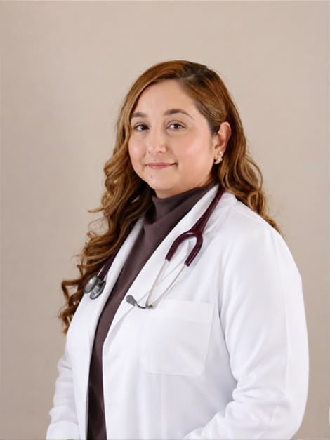 Female doctor wearing white lab coat and stethoscope with brown hair against neutral background